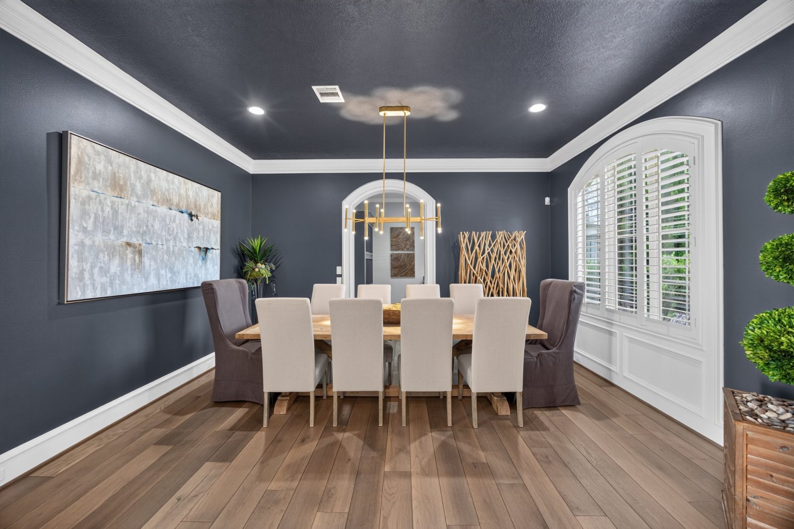 Navy dining room with a gold chandelier and long wood table