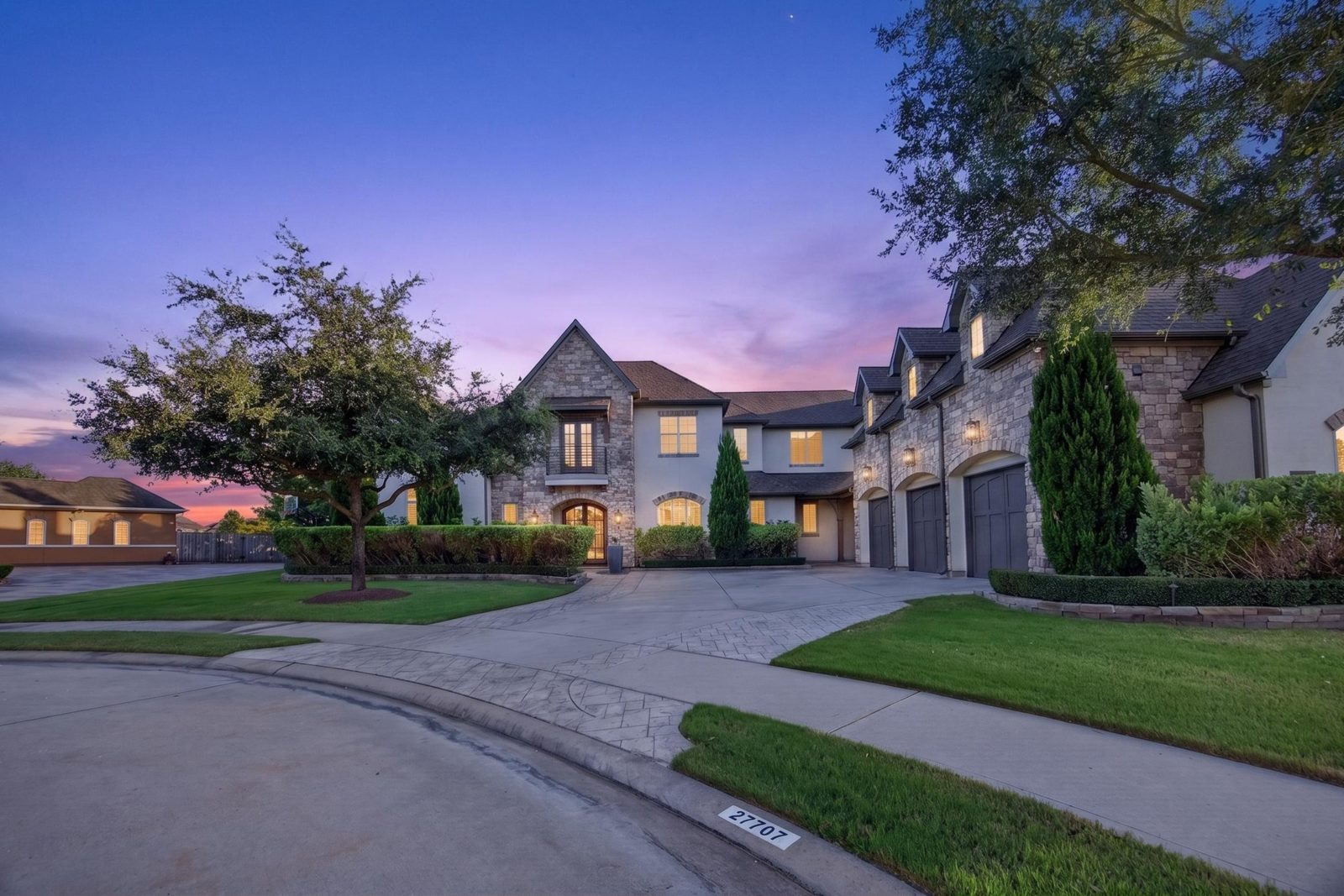 Stone two-story home at sunset with a three-car garage